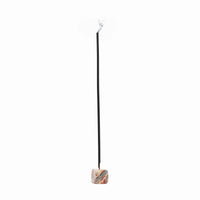 Single black incense stick displayed upright in a small marbled stone holder.